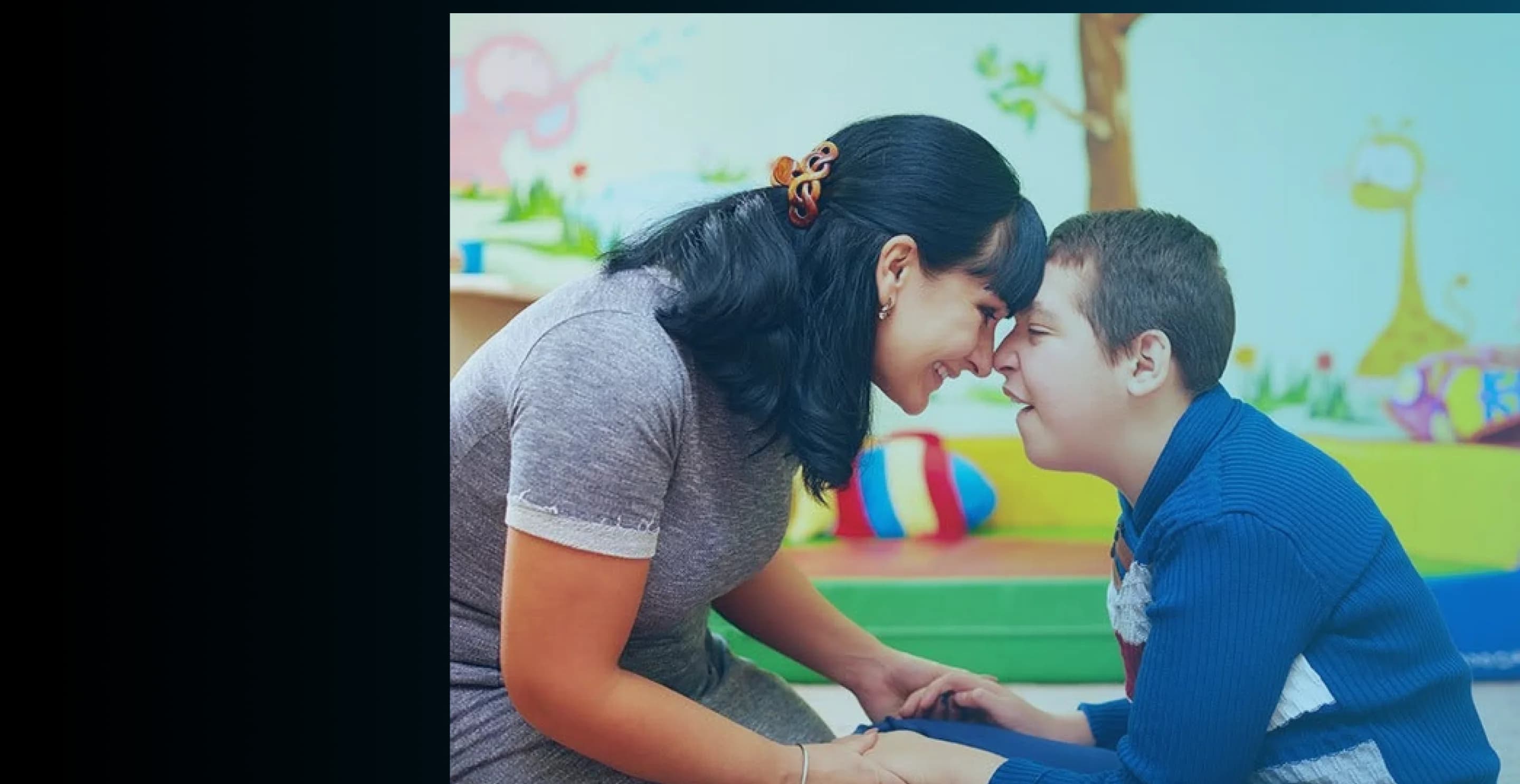 A support worker and child smiling together at ASHO
